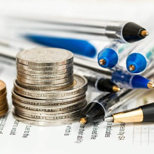 a stack of coins next to some pens